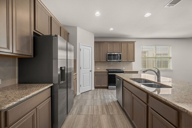 205 Falkland St, Hutto, TX 78634 - kitchen with stainless steel appliances, backsplash, light stone counters, and recessed lighting