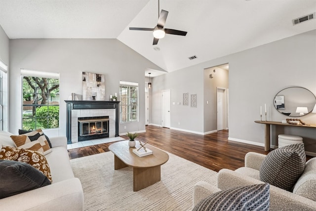 8204 Cahill Dr, Austin, TX 78729 - living area featuring wood finished floors, healthy amount of natural light, a ceiling fan, a tile fireplace, and high vaulted ceiling
