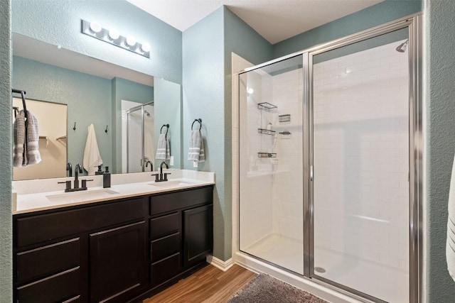 316 Shiner Ln, Georgetown, TX 78626 - full bathroom with wood finished floors, a stall shower, double vanity, and a textured wall