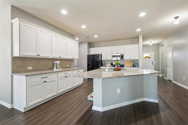 316 Shiner Ln, Georgetown, TX 78626 - kitchen featuring stainless steel microwave, black fridge, dark wood finished floors, tasteful backsplash, and white cabinetry