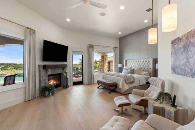 1216 Travis Bluff Way, Spicewood, TX 78669 - bedroom featuring access to outside, multiple windows, hardwood / wood-style floors, a tiled fireplace, and recessed lighting