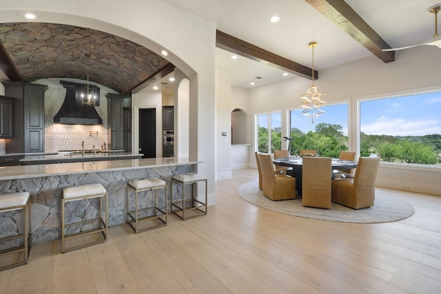 1216 Travis Bluff Way, Spicewood, TX 78669 - dining space featuring arched walkways, a chandelier, plenty of natural light, and light wood-style flooring