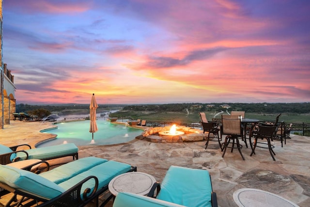 1216 Travis Bluff Way, Spicewood, TX 78669 - patio terrace at dusk with a patio, an outdoor fire pit, an outdoor pool, and outdoor dining area