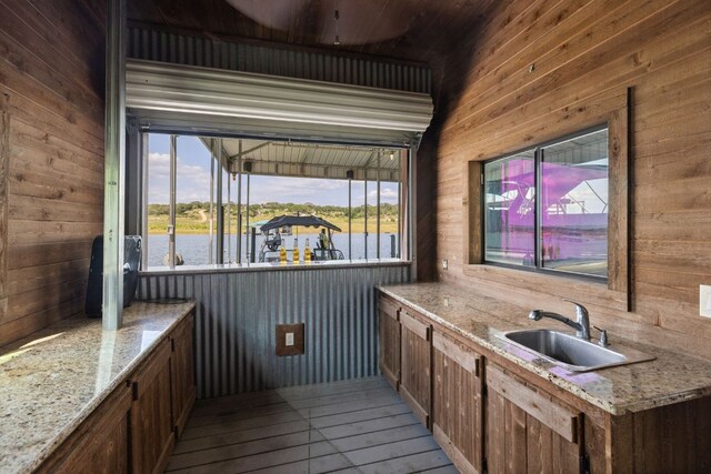 1216 Travis Bluff Way, Spicewood, TX 78669 - kitchen with wooden walls, plenty of natural light, light wood finished floors, light stone countertops, and a water view