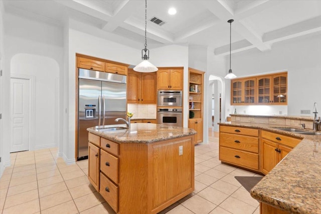 2905 Post River Rd, Cedar Park, TX 78613 - kitchen featuring coffered ceiling, arched walkways, appliances with stainless steel finishes, light tile patterned flooring, and light stone countertops