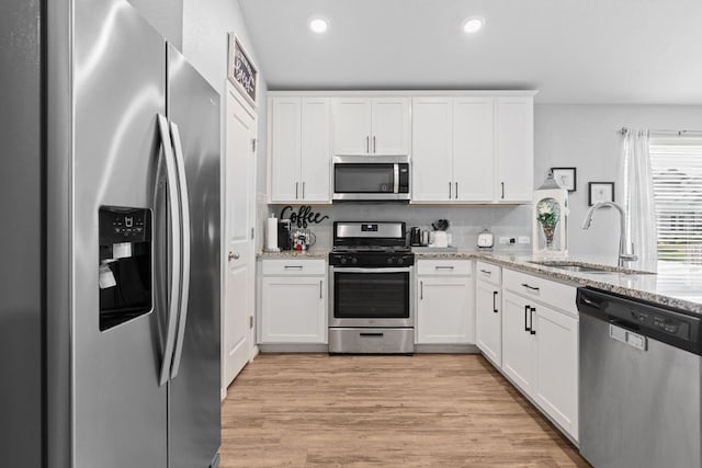 6045 Teodoro Bnd, Round Rock, TX 78665 - kitchen with appliances with stainless steel finishes, recessed lighting, white cabinets, light stone counters, and light wood finished floors