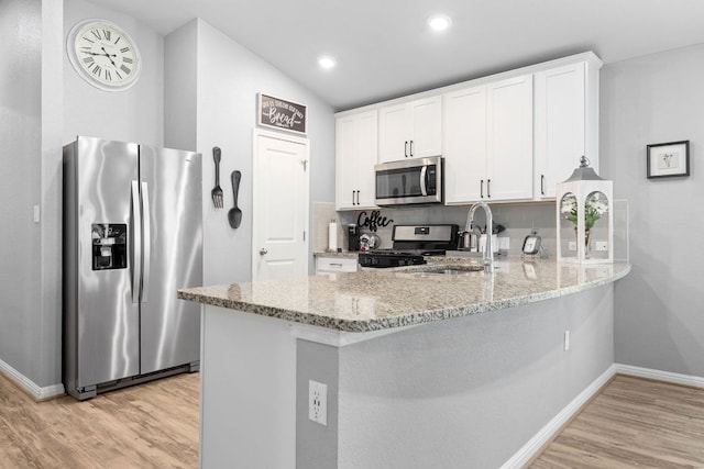 6045 Teodoro Bnd, Round Rock, TX 78665 - kitchen featuring appliances with stainless steel finishes, light wood-type flooring, a peninsula, light stone counters, and white cabinetry