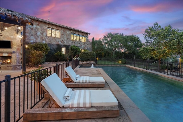 205 Hi Ridge Rd, Horseshoe Bay, TX 78657 - pool at dusk with an outdoor stone fireplace and a patio