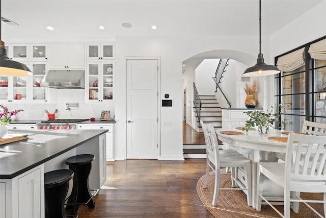 205 Hi Ridge Rd, Horseshoe Bay, TX 78657 - kitchen with under cabinet range hood, dark wood finished floors, arched walkways, white cabinets, and recessed lighting