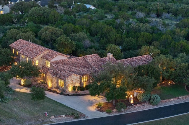 205 Hi Ridge Rd, Horseshoe Bay, TX 78657 - view of front facade featuring a chimney, stone siding, a forest view, a tile roof, and concrete driveway