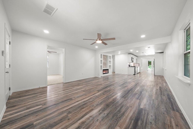 7309 Blessing Ave, Austin, TX 78752 - unfurnished living room with a ceiling fan, dark wood-type flooring, a warm lit fireplace, and recessed lighting