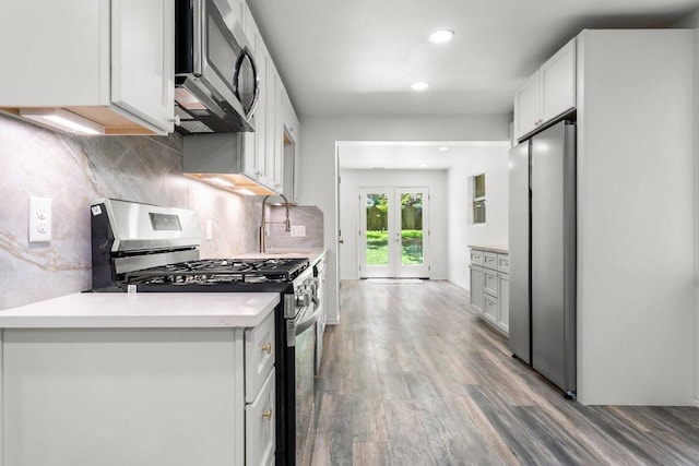 7309 Blessing Ave, Austin, TX 78752 - kitchen with appliances with stainless steel finishes, wood finished floors, backsplash, light countertops, and french doors
