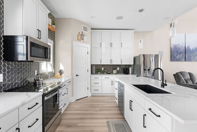 TBD Fm 3000, Elgin, TX 78621 - kitchen featuring stainless steel appliances, light wood finished floors, tasteful backsplash, white cabinets, and hanging light fixtures