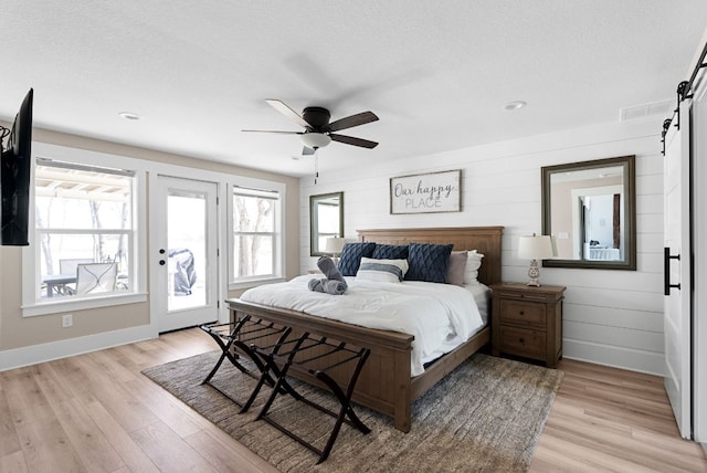 TBD Fm 3000, Elgin, TX 78621 - bedroom with a barn door, access to exterior, light wood-style floors, a ceiling fan, and a textured ceiling