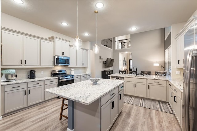 24822 Levante Dr, Richmond, TX 77406 - kitchen with appliances with stainless steel finishes, a peninsula, light wood-type flooring, decorative backsplash, and a kitchen island