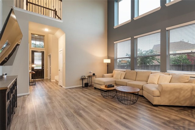 24822 Levante Dr, Richmond, TX 77406 - living room featuring a high ceiling, healthy amount of natural light, light wood-style floors, and arched walkways