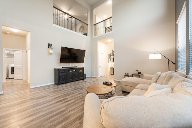 24822 Levante Dr, Richmond, TX 77406 - living room featuring light wood-style floors, a high ceiling, and washer / dryer