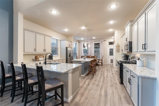 24822 Levante Dr, Richmond, TX 77406 - kitchen with stainless steel appliances, a breakfast bar area, decorative backsplash, a center island, and recessed lighting