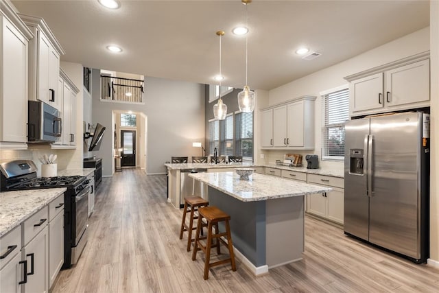 24822 Levante Dr, Richmond, TX 77406 - kitchen featuring appliances with stainless steel finishes, a peninsula, tasteful backsplash, light wood-type flooring, and plenty of natural light