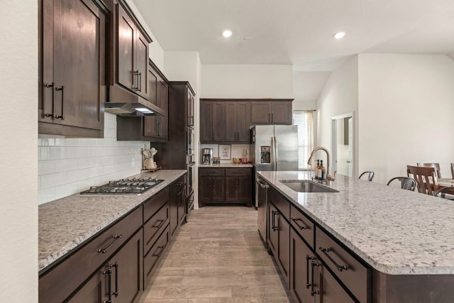 232 Silver Pass, Kyle, TX 78640 - kitchen featuring under cabinet range hood, appliances with stainless steel finishes, dark brown cabinets, a center island with sink, and light stone counters