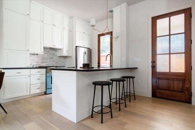 3003 W French Pl Unit 1, Austin, TX 78722 - kitchen with appliances with stainless steel finishes, light wood-style floors, dark countertops, white cabinets, and tasteful backsplash