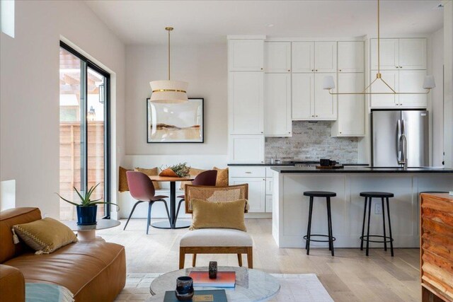 3003 W French Pl Unit 1, Austin, TX 78722 - kitchen featuring freestanding refrigerator, dark countertops, tasteful backsplash, a kitchen bar, and white cabinets