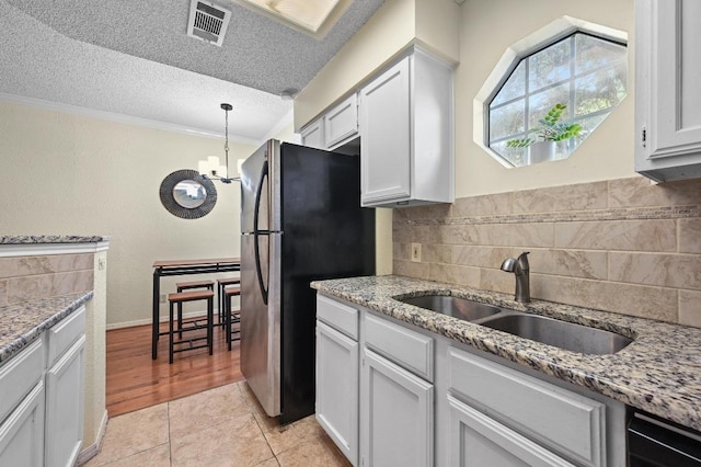 3111 Tom Green St Unit 203, Austin, TX 78705 - kitchen with freestanding refrigerator, backsplash, light tile patterned floors, a chandelier, and light stone counters