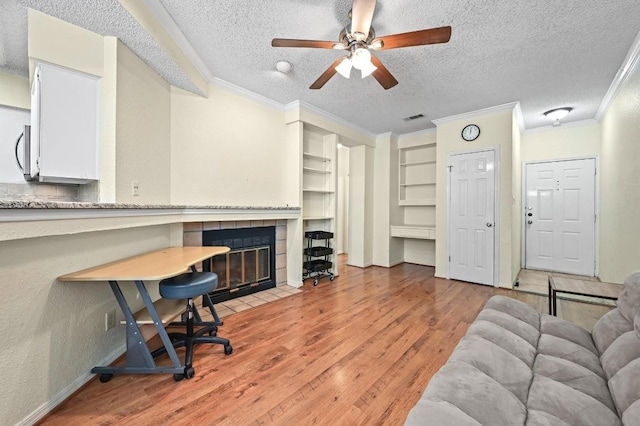 3111 Tom Green St Unit 203, Austin, TX 78705 - home office with a textured ceiling, ornamental molding, light wood-type flooring, a ceiling fan, and a tiled fireplace