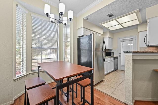 3111 Tom Green St Unit 203, Austin, TX 78705 - kitchen featuring stainless steel appliances, ornamental molding, a chandelier, a textured ceiling, and a textured wall