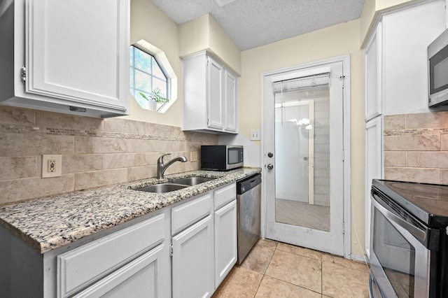 3111 Tom Green St Unit 203, Austin, TX 78705 - kitchen featuring stainless steel appliances, light stone countertops, white cabinets, backsplash, and a textured ceiling