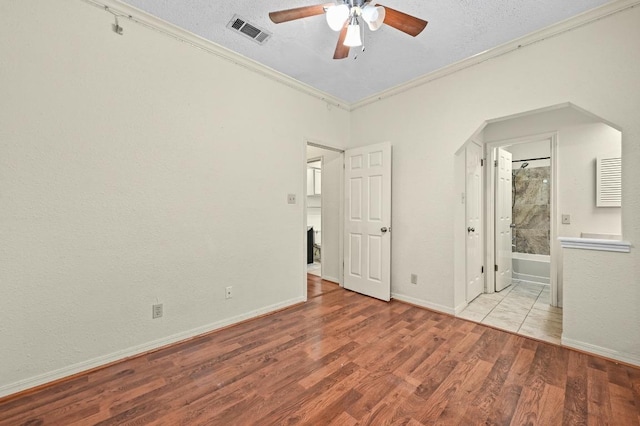 3111 Tom Green St Unit 203, Austin, TX 78705 - unfurnished bedroom featuring crown molding, wood finished floors, a textured ceiling, connected bathroom, and arched walkways