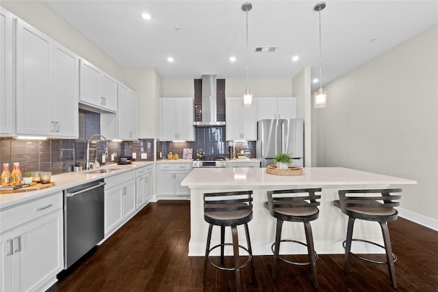 4501 Jackson Ave Unit 5301, Austin, TX 78731 - kitchen featuring appliances with stainless steel finishes, wall chimney range hood, a center island, a kitchen breakfast bar, and decorative backsplash