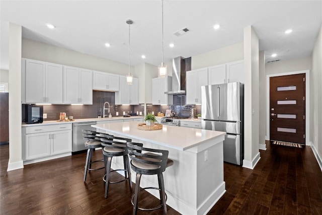 4501 Jackson Ave Unit 5301, Austin, TX 78731 - kitchen with stainless steel appliances, wall chimney range hood, a kitchen island, light countertops, and dark wood-type flooring