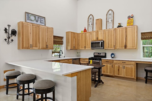 705 Peregrine Way, Leander, TX 78641 - kitchen with appliances with stainless steel finishes, a high ceiling, a kitchen breakfast bar, a peninsula, and light countertops