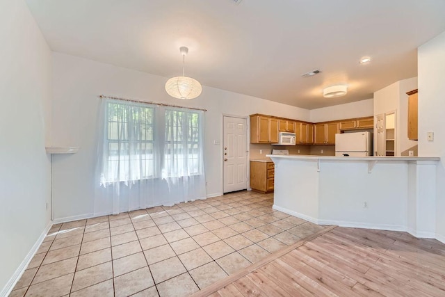 2920 Thrushwood Dr, Austin, TX 78757 - kitchen with white appliances, light countertops, a peninsula, light wood-style floors, and pendant lighting