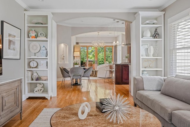4206 Sinclair Ave, Austin, TX 78756 - living room featuring a chandelier, built in shelves, arched walkways, light wood-style flooring, and ornamental molding