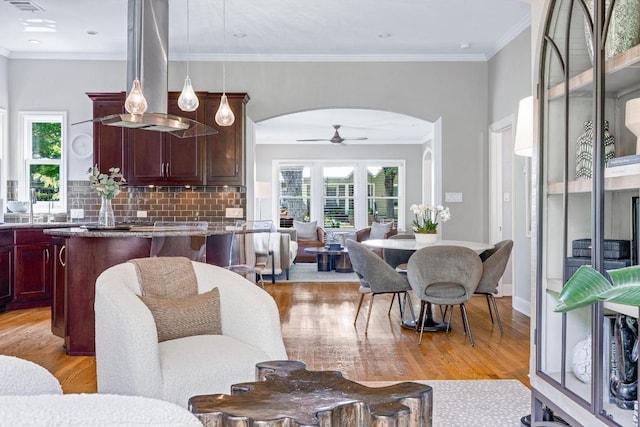 4206 Sinclair Ave, Austin, TX 78756 - living room with arched walkways, light wood-style floors, healthy amount of natural light, ceiling fan, and ornamental molding