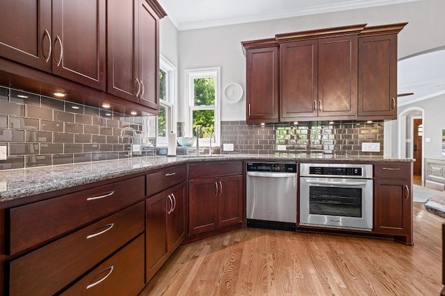 4206 Sinclair Ave, Austin, TX 78756 - kitchen featuring stainless steel appliances, light wood-style flooring, ornamental molding, tasteful backsplash, and light stone countertops