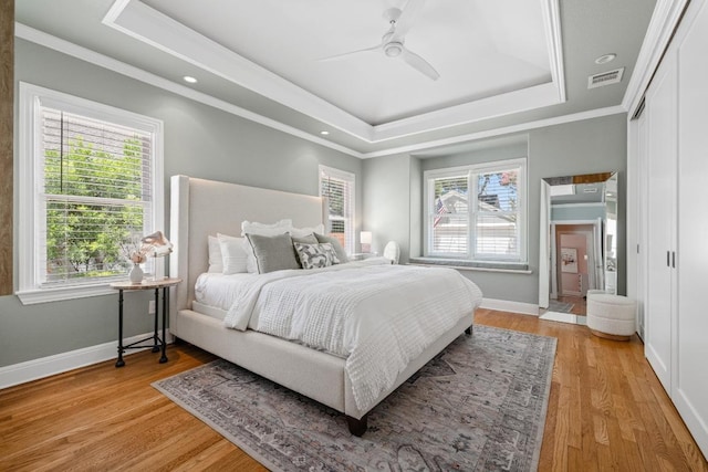 4206 Sinclair Ave, Austin, TX 78756 - bedroom featuring a raised ceiling, multiple windows, light wood-style floors, ornamental molding, and a ceiling fan