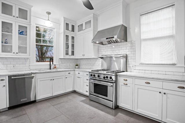 607 W 32nd St, Austin, TX 78705 - kitchen featuring wall chimney range hood, appliances with stainless steel finishes, light tile patterned floors, and white cabinets