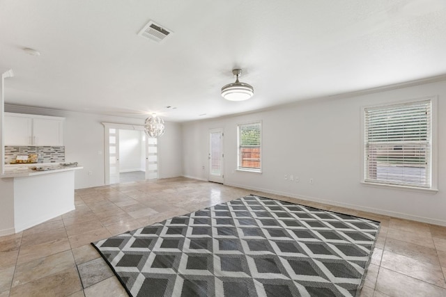 6828 Walkup Ln, Austin, TX 78747 - unfurnished living room with light tile patterned floors, a chandelier, and ornamental molding