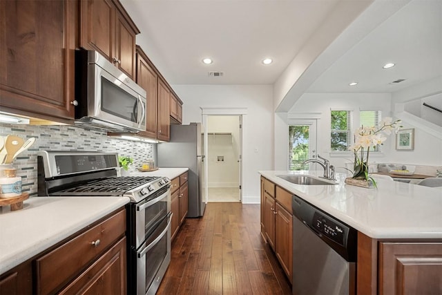 11013 Avery Station Loop Unit 31, Austin, TX 78717 - kitchen with stainless steel appliances, tasteful backsplash, dark wood-style floors, light countertops, and an island with sink