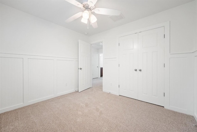 11013 Avery Station Loop Unit 31, Austin, TX 78717 - unfurnished bedroom with a decorative wall, light colored carpet, a wainscoted wall, a ceiling fan, and a closet