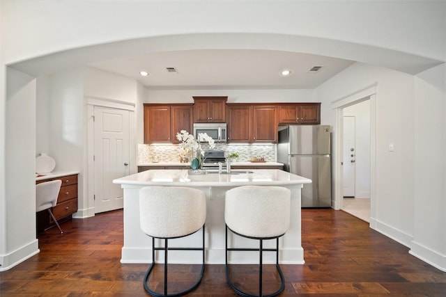 11013 Avery Station Loop Unit 31, Austin, TX 78717 - kitchen featuring stainless steel appliances, light countertops, a kitchen island with sink, backsplash, and dark wood-style floors