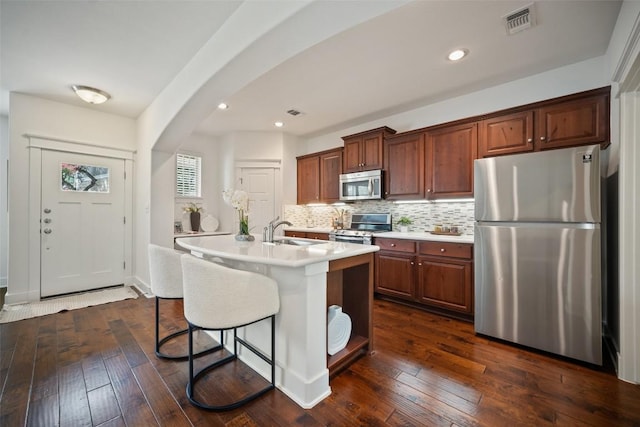 11013 Avery Station Loop Unit 31, Austin, TX 78717 - kitchen with stainless steel appliances, light countertops, arched walkways, tasteful backsplash, and dark wood finished floors