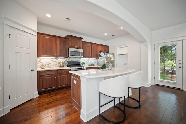 11013 Avery Station Loop Unit 31, Austin, TX 78717 - kitchen featuring stainless steel appliances, light countertops, tasteful backsplash, dark wood-type flooring, and a kitchen island with sink