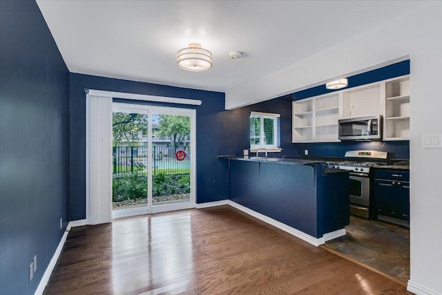 1210 Windsor Rd Unit 113, Austin, TX 78703 - kitchen with appliances with stainless steel finishes, open shelves, dark countertops, a peninsula, and dark wood finished floors