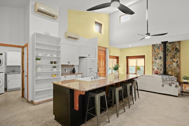 913 Taulbee Ln, Austin, TX 78757 - kitchen featuring a ceiling fan, a wall mounted AC, estacked washer and dryer, and a towering ceiling