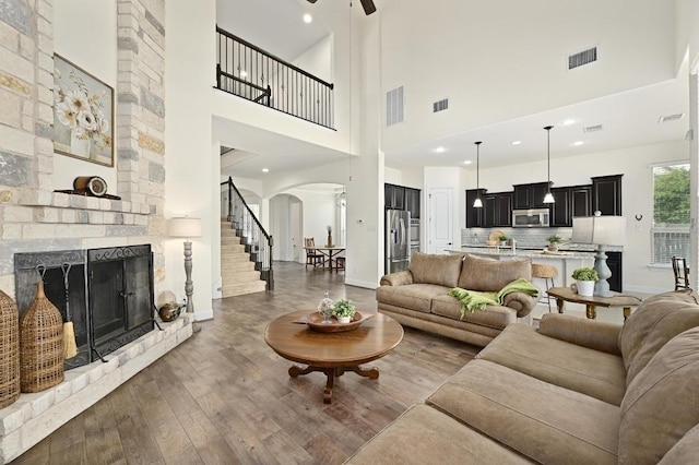 1113 Hartman Dr, Leander, TX 78641 - living room with arched walkways, a towering ceiling, wood finished floors, a fireplace, and stairway