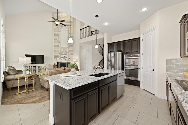 1113 Hartman Dr, Leander, TX 78641 - kitchen featuring stainless steel appliances, light tile patterned floors, ceiling fan, high vaulted ceiling, and light stone countertops